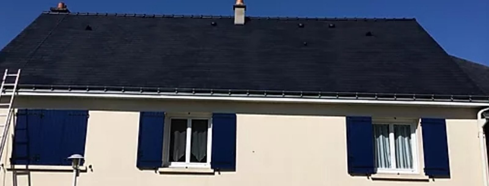 Toiture en ardoise sombre et propre après démoussage, sous un ciel bleu
