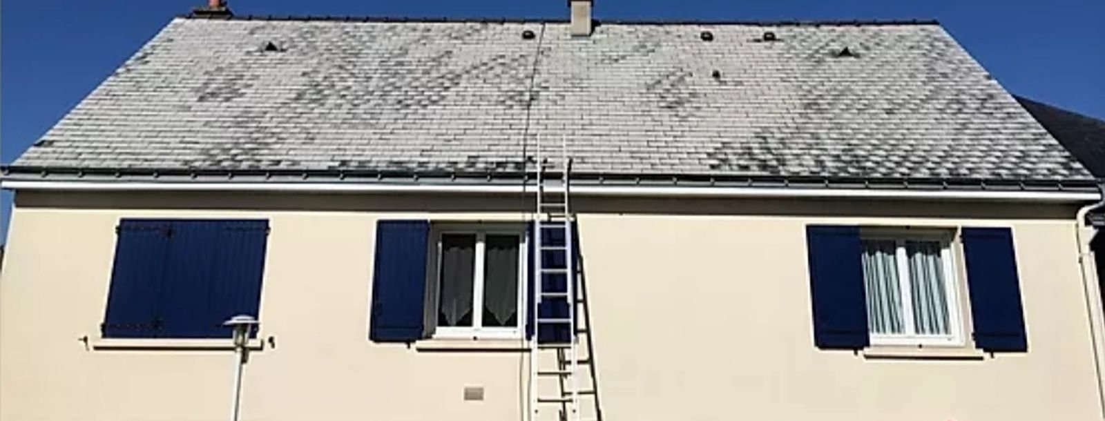 Toiture en ardoise grisée par les mousses et les lichens avant démoussage